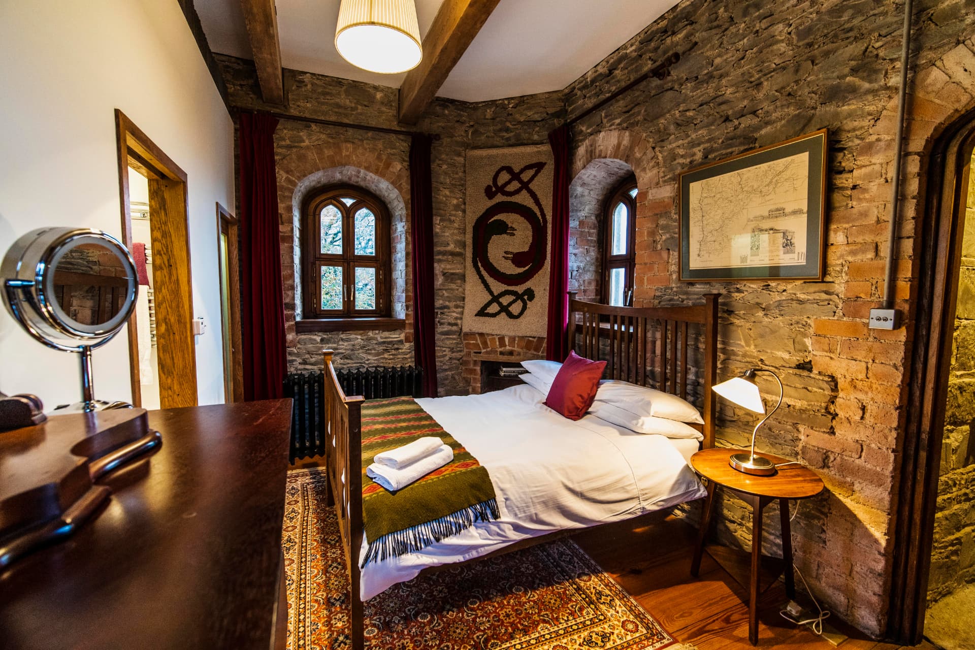 The circular stone bedroom inside Drummond Tower with arched windows and wooden beams