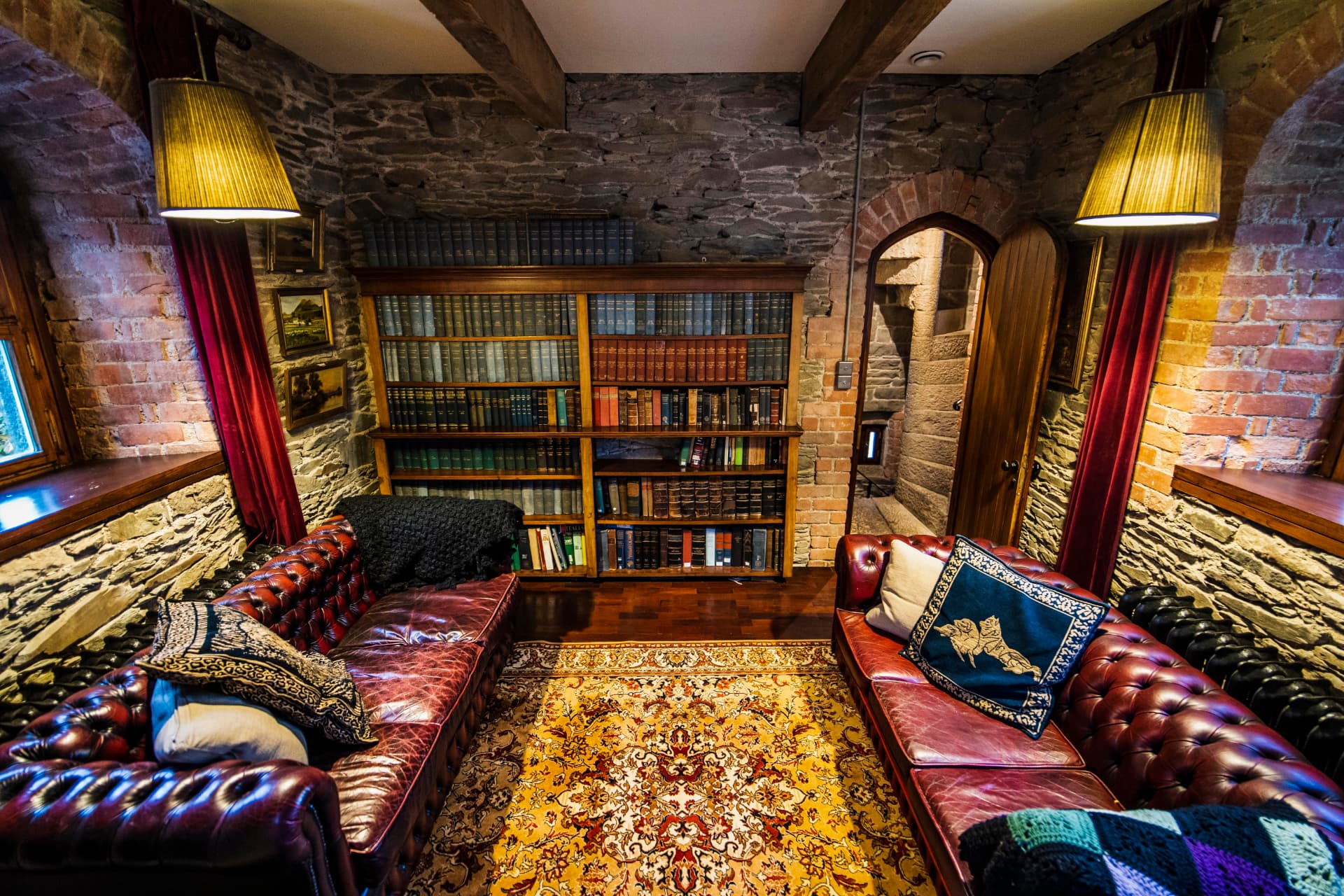 The stone walled library at Drummond Tower with leather sofas and floor to ceiling bookshelves
