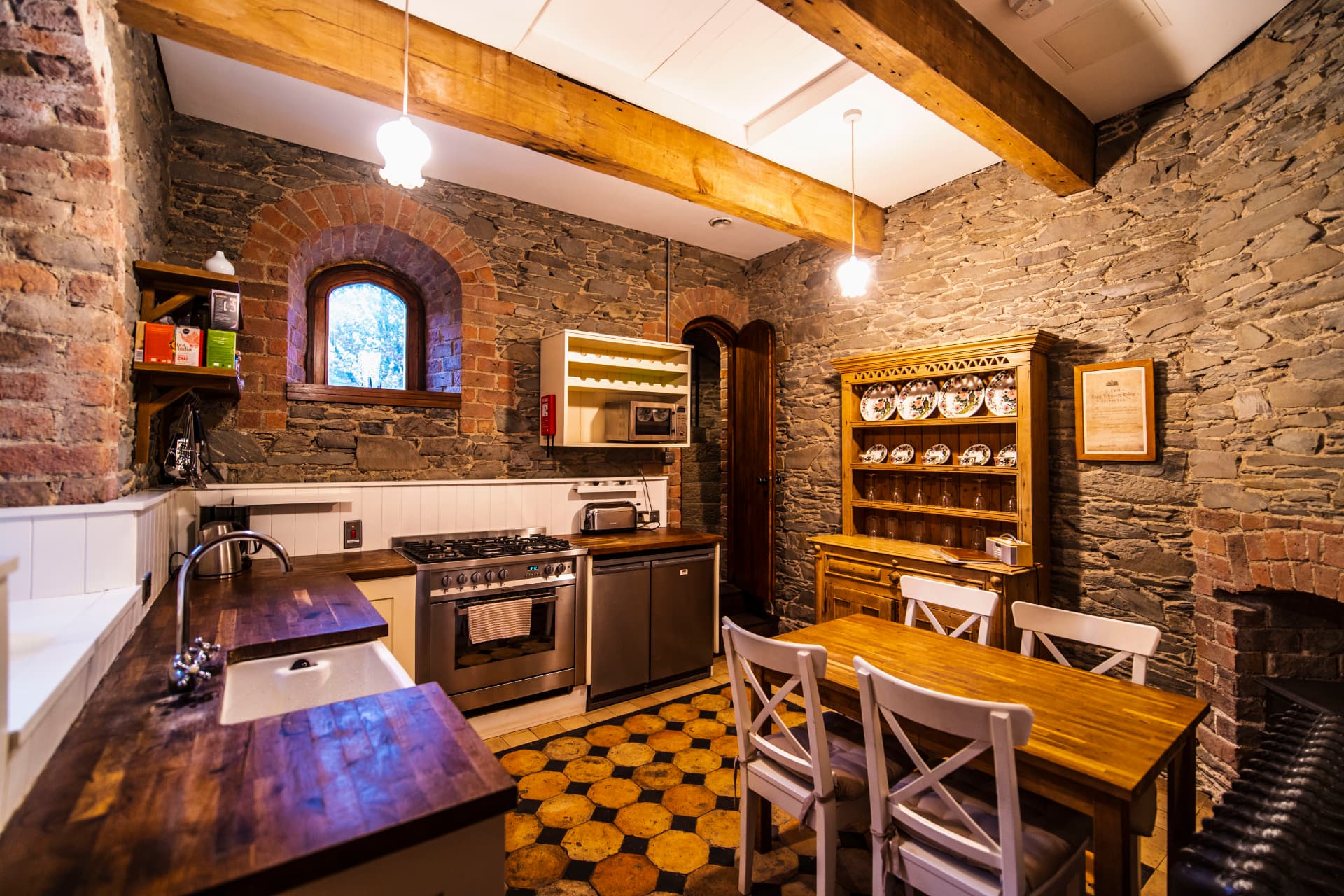 The rustic kitchen and dining space at Drummond Tower with exposed stone and timber beams